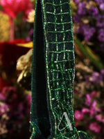 Close-up of a green beaded strap with a blurred floral background