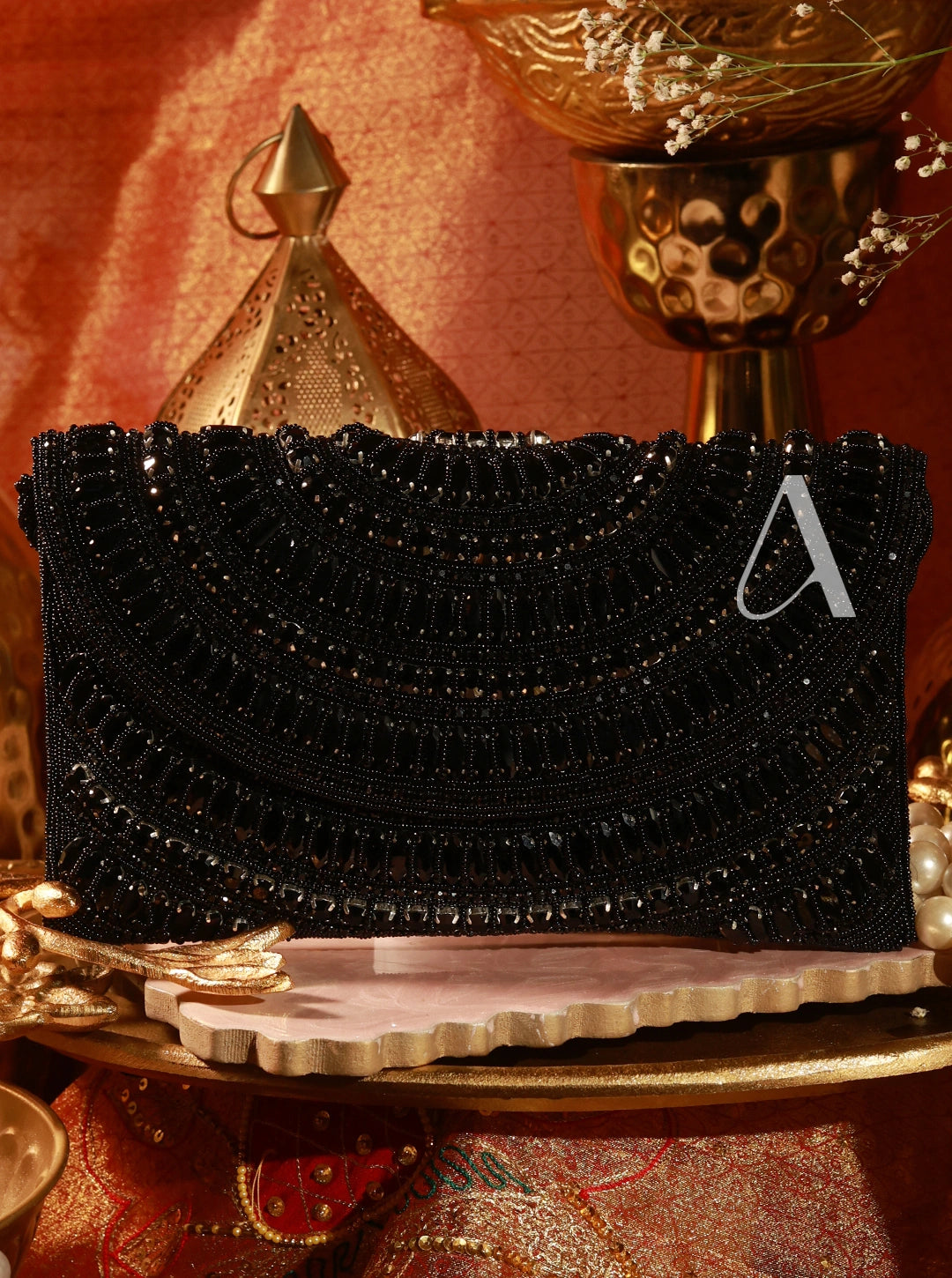 Black beaded clutch bag on a decorative stand with a gold trophy in the background