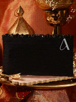 Black rectangular box with a white letter 'A' on a decorative surface with gold and red elements.