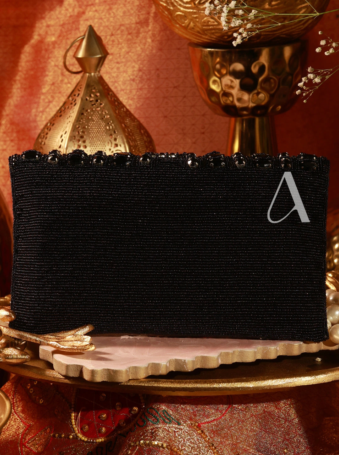 Black rectangular box with a white letter 'A' on a decorative surface with gold and red elements.