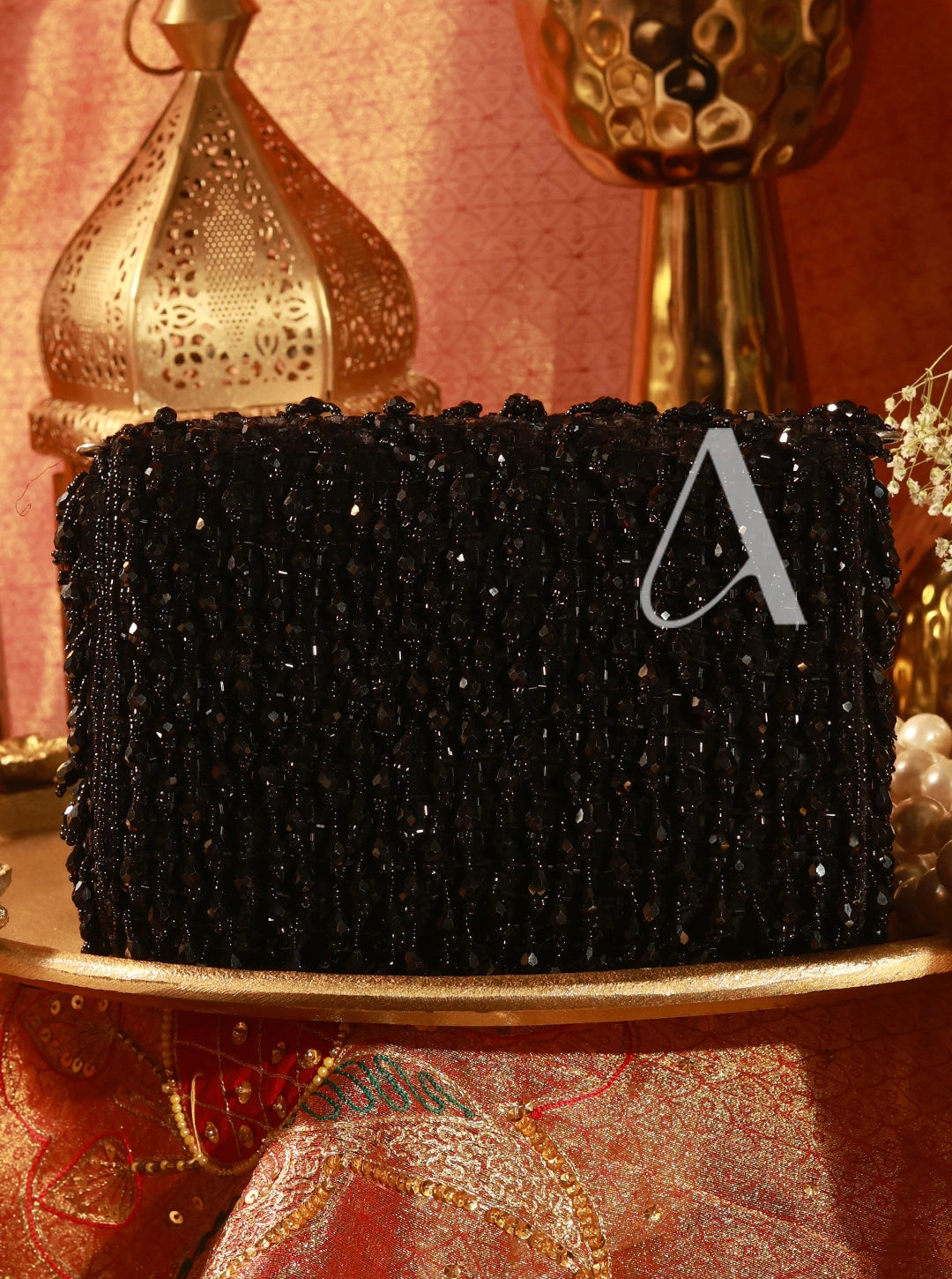 Black beaded clutch with a letter 'A' on a decorative surface
