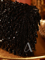 Close-up of a black beaded clutch bag with a blurred background