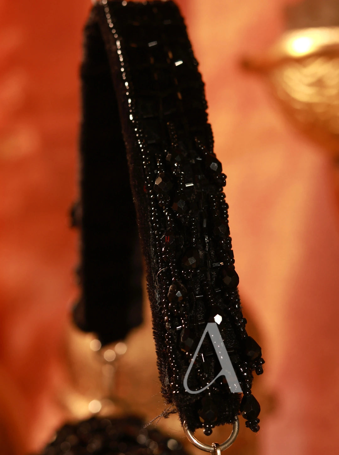 Black beaded strap with a gold clasp on a blurred background