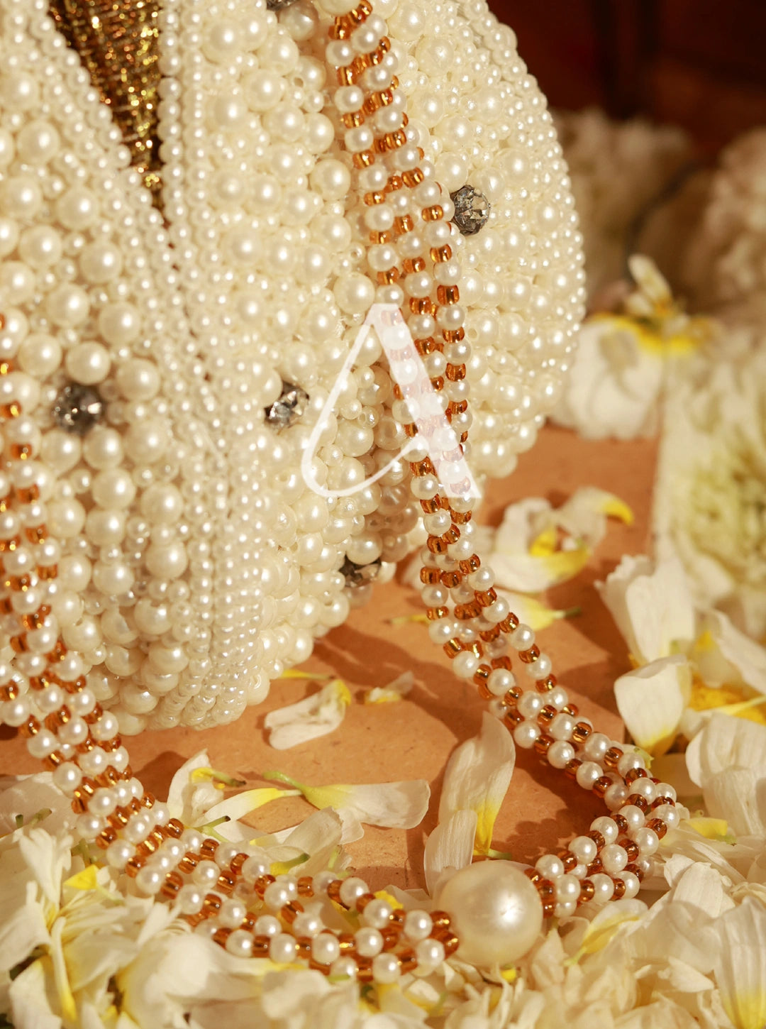 Close-up of pearl necklaces and flowers on a wooden surface