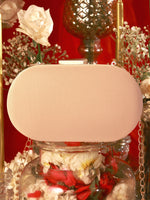 Beige clutch bag on a decorative stand with flowers and a red background