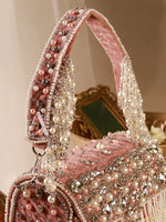 Pink handbag with pearl and crystal embellishments on a neutral background