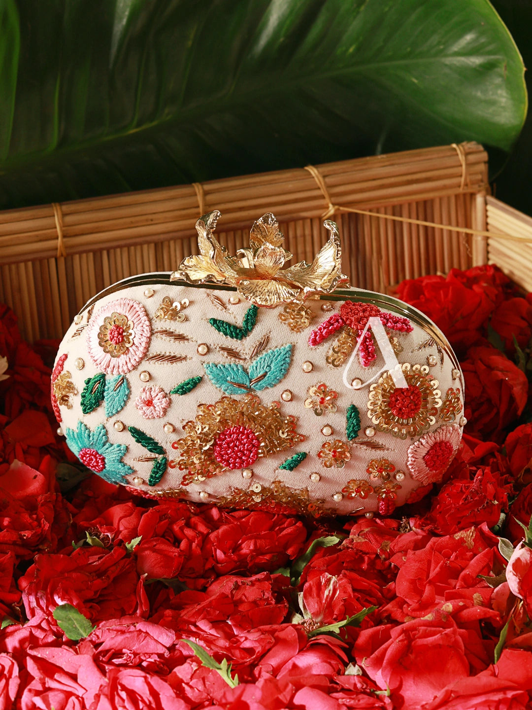 Decorative clutch bag with floral patterns on a bed of red roses