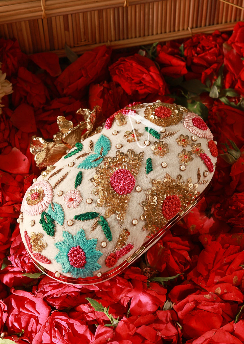 Decorative clutch bag with floral embroidery on a bed of red flowers