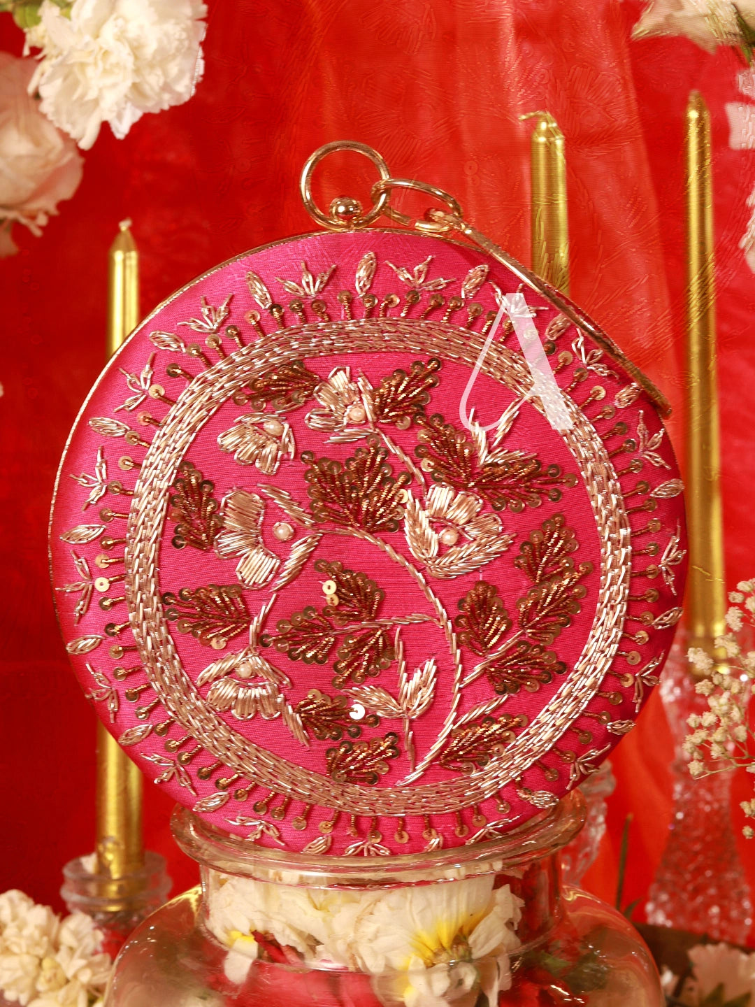 Decorative pink and gold round object with floral patterns on a red background