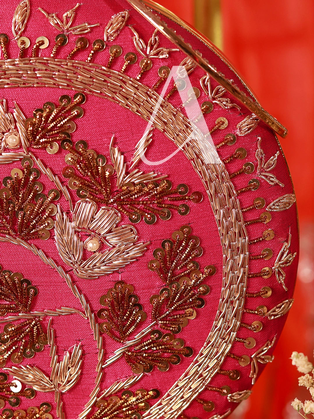 Close-up of a pink fabric with gold embroidery on a red background