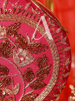 Close-up of a pink fabric with gold embroidery on a red background