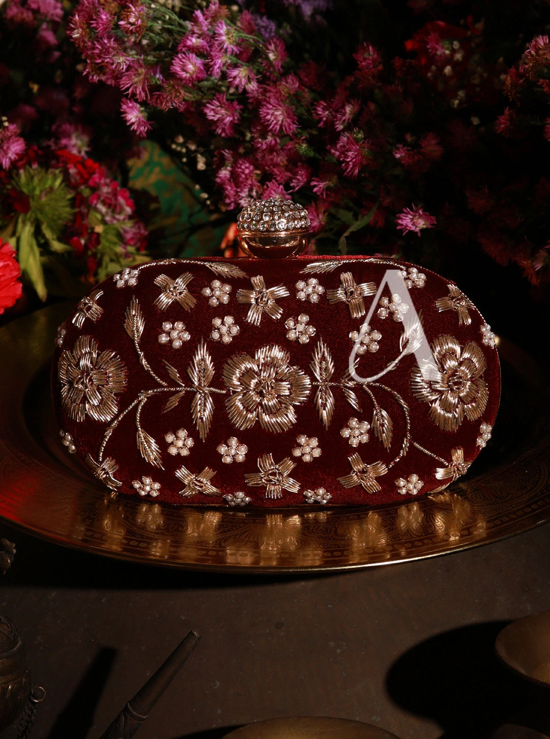 Decorative clutch bag with floral patterns and a letter 'A' on a dark background