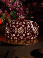 Decorative clutch bag with floral patterns and a letter 'A' on a dark background