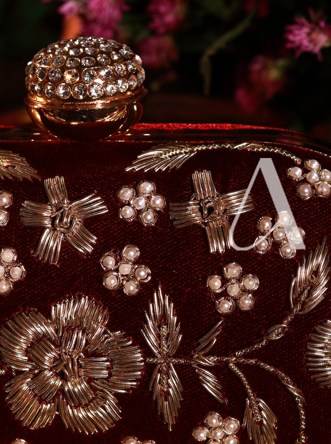 Decorative clutch with floral and leaf patterns and a letter 'A' on a dark background