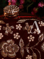 Decorative clutch with floral and leaf patterns and a letter 'A' on a dark background