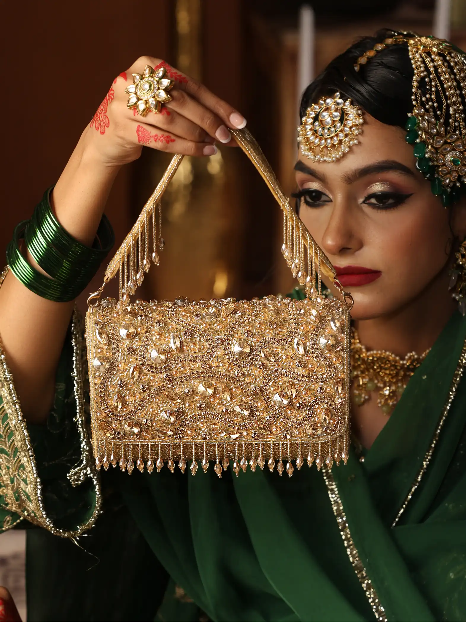 Woman holding a gold beaded handbag with intricate designs, wearing traditional jewelry.