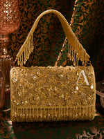 Gold handbag with intricate designs and embellishments on a patterned background