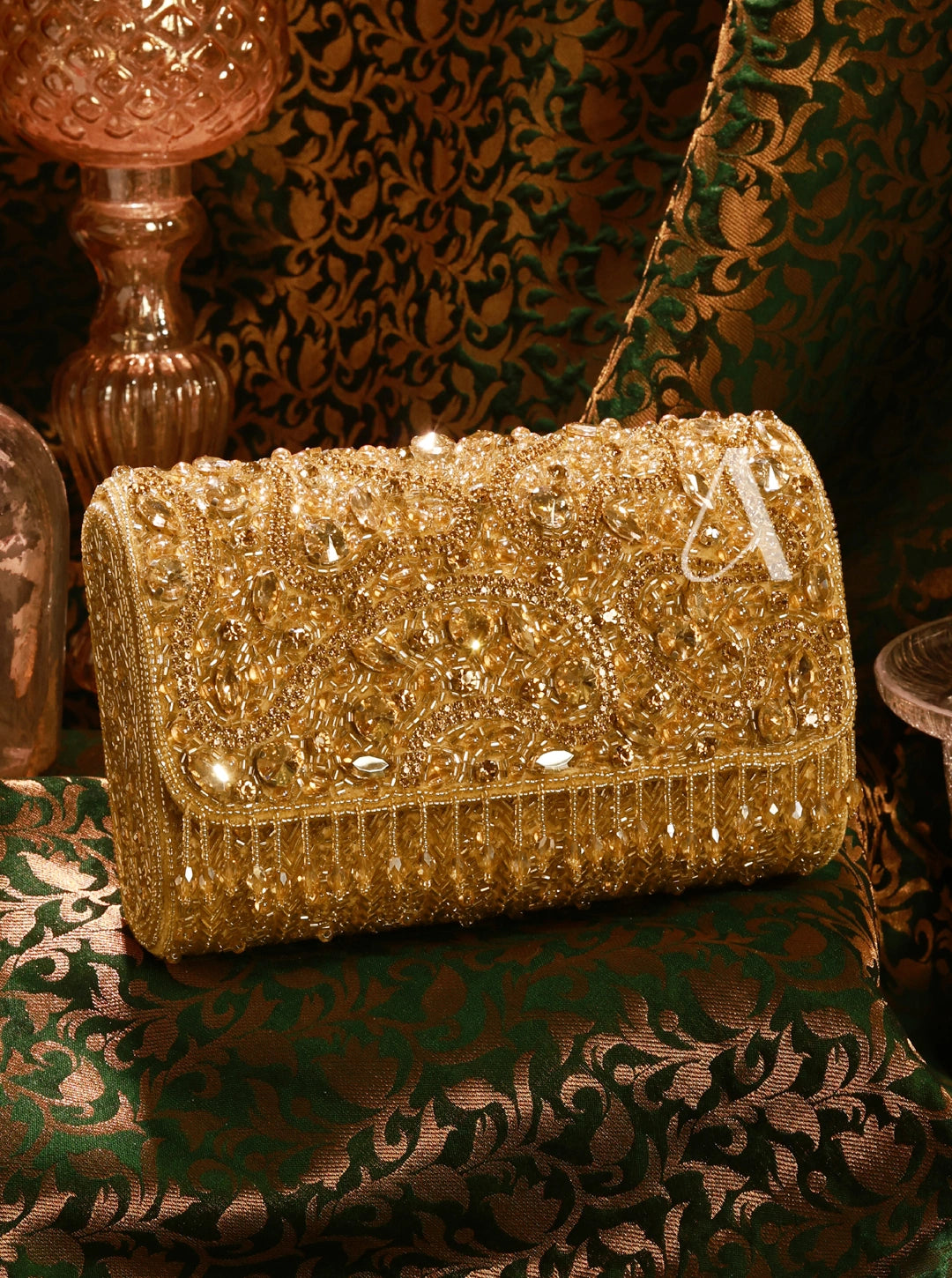 Gold beaded clutch bag on a decorative surface with a patterned background