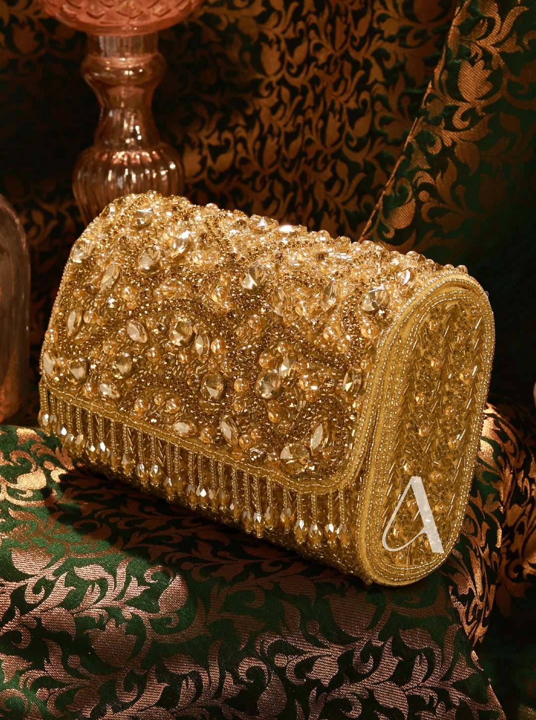 Gold beaded clutch bag on a patterned fabric background