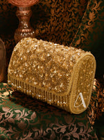 Gold beaded clutch bag on a patterned fabric background