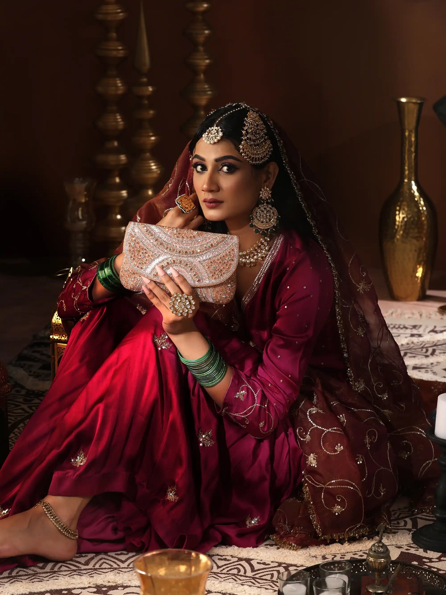 Woman in traditional attire holding a decorative item in a warm-toned room.