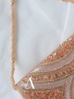 Close-up of a decorative bag with intricate patterns and a gold chain on a white background.
