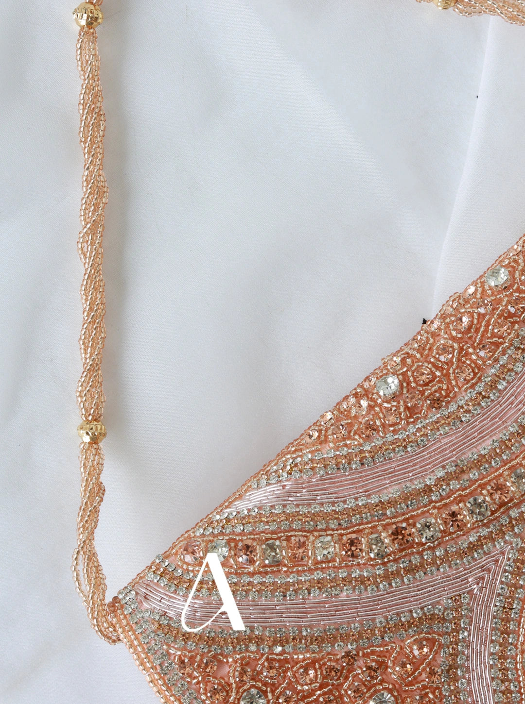 Close-up of a decorative bag with intricate patterns and a gold chain on a white background.