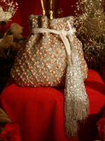 Decorative bag with beads and tassel on a red surface with flowers in the background