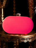 Pink clutch bag on a decorative table with a dark background