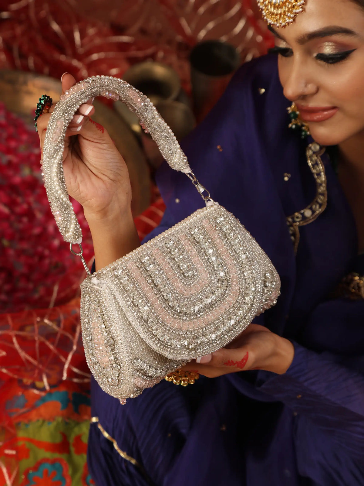 Woman holding a silver beaded handbag with a colorful background