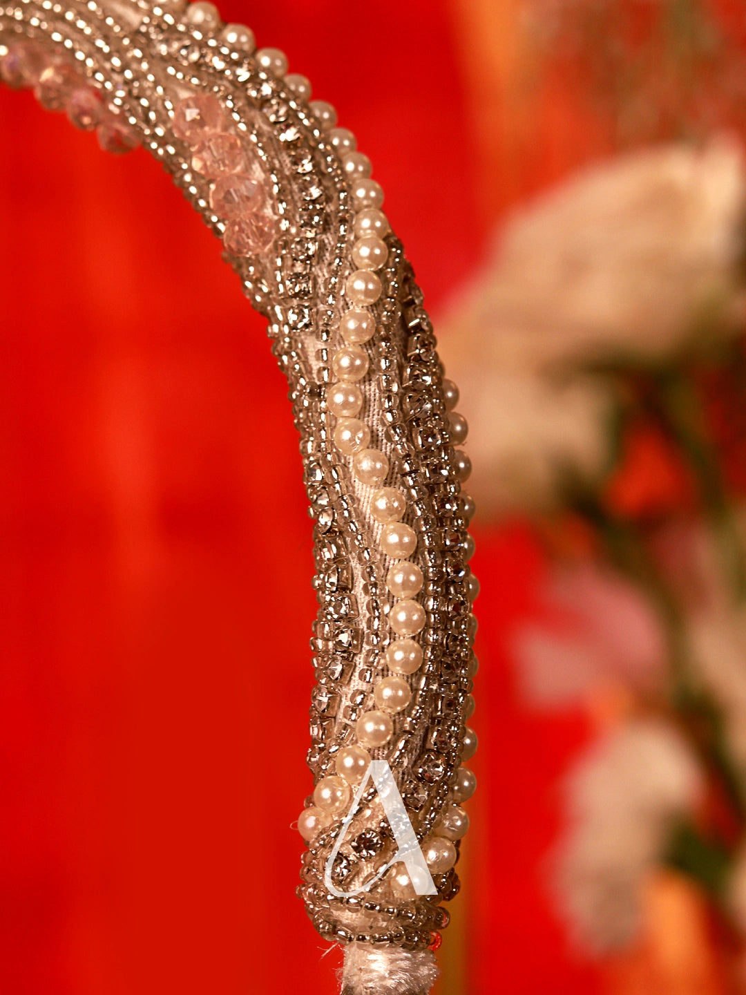 Close-up of a decorative headband with pearls against a red background