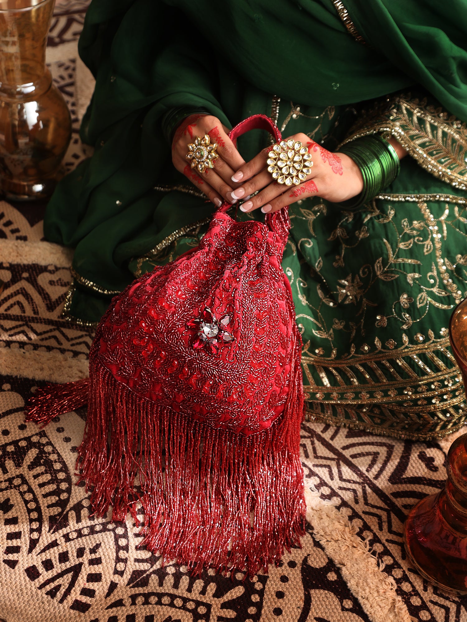 Person holding a red embroidered bag with intricate patterns on a patterned fabric background