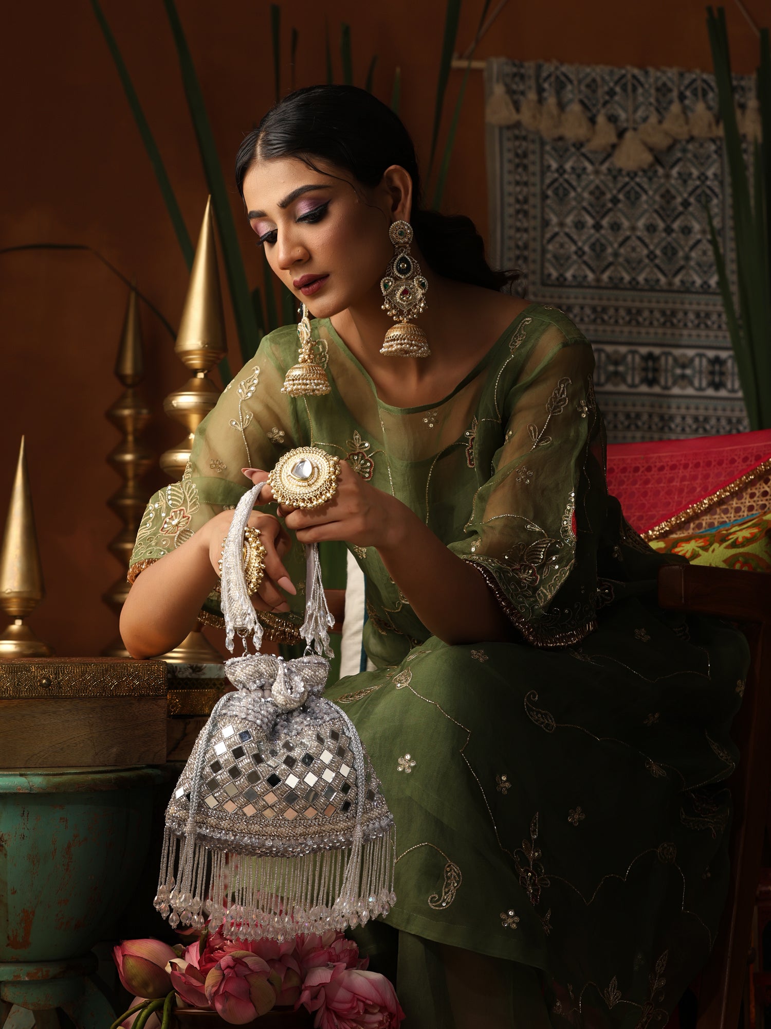 Woman in traditional attire holding a decorative bag with intricate designs.